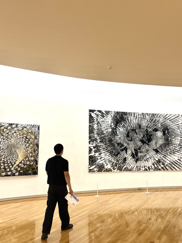 Visitor viewing large contemporary artworks in a bright Mimesis Art Museum gallery
