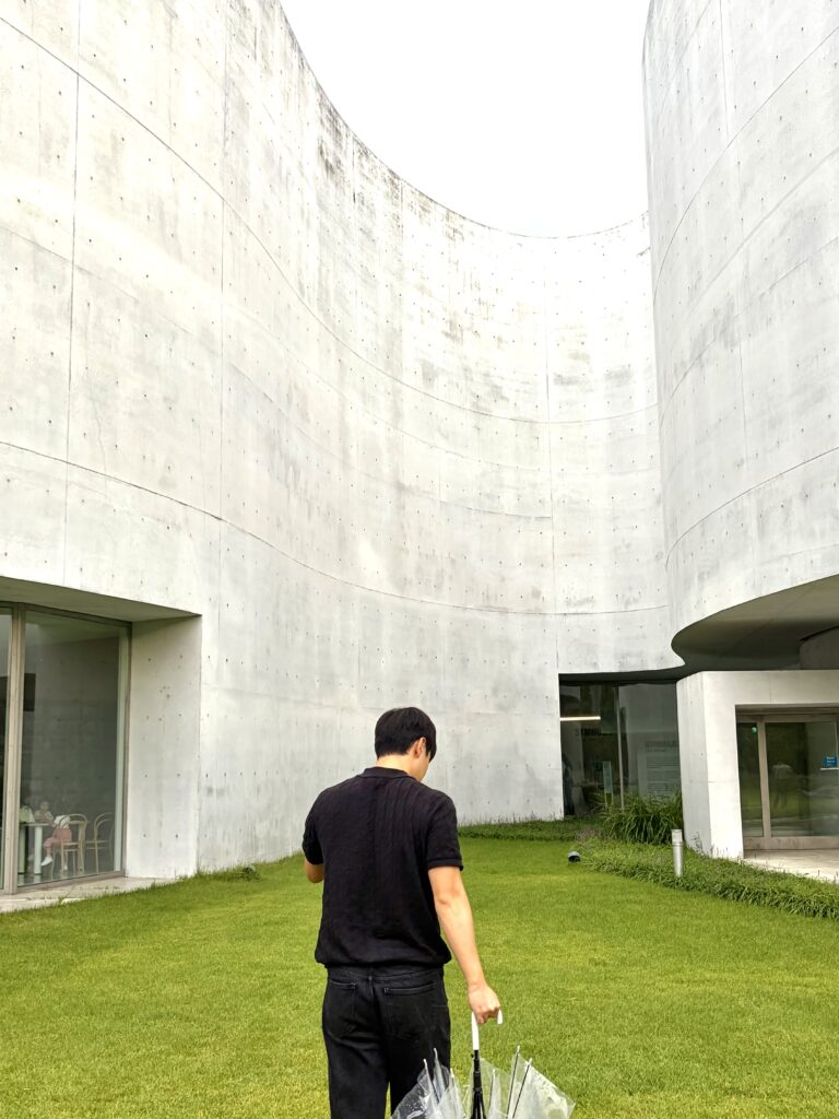 Curved pale concrete exterior walls and lawn at Mimesis Art Museum in Paju