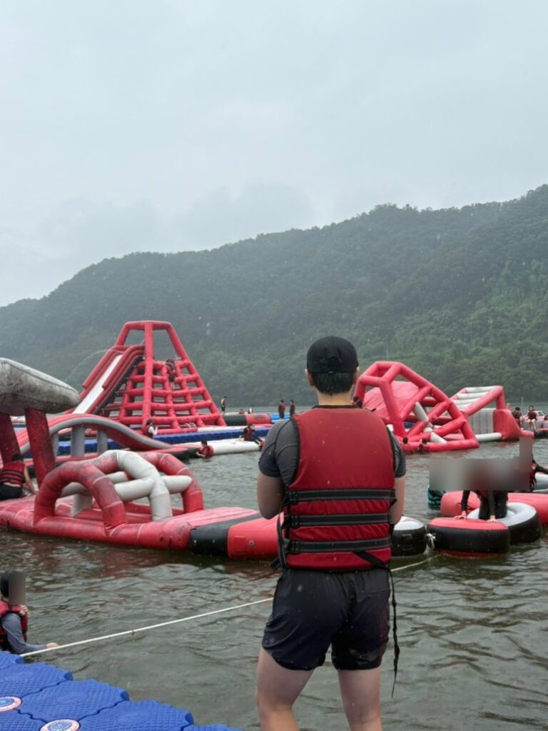 Traveler in a life jacket looking toward the floating water park at Ten Park