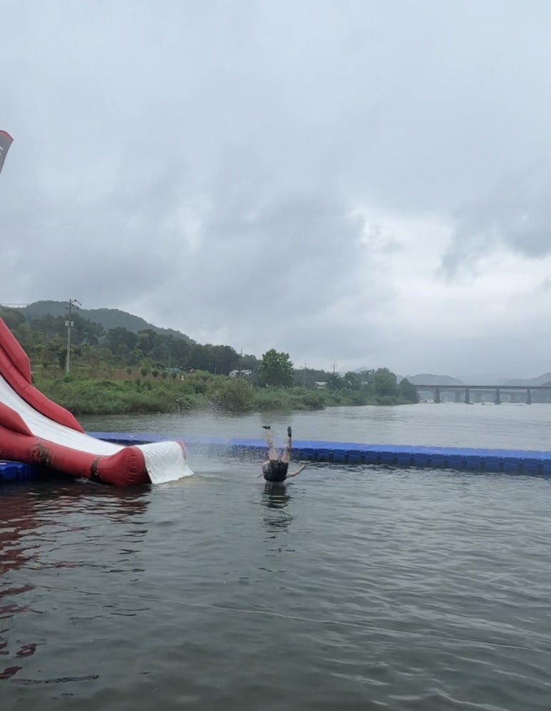 Visitor landing in the water beside a red slide at Ten Park
